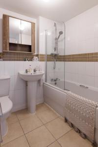 uma casa de banho com um lavatório, uma banheira e um WC. em Comfortable 4-Bedroom Home in Aylesbury Ideal for Contractors Professionals or Larger Families em Aylesbury
