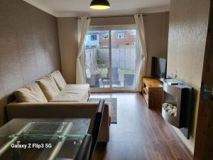 a living room with a couch and a table and a tv at APNI HOMES! in Birstall