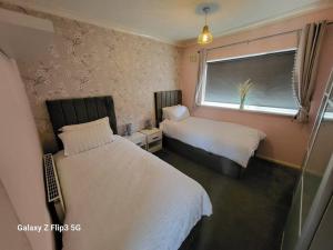 1 dormitorio con 2 camas y ventana en APNI HOMES!, en Birstall