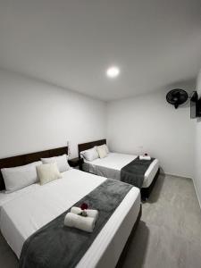2 camas en una habitación de hotel con paredes blancas en Hotel el tamaco, en Ocaña