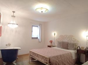a bedroom with a bed and a tub and a chandelier at Gerês e Cabreira - Romoa Vintage Guest House in Vieira do Minho