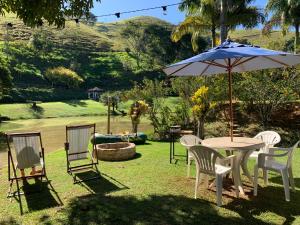 een tafel en stoelen met een parasol in het gras bij Casinha de Campo com Lago Sítio Luar do Sertão in Bom Jardim