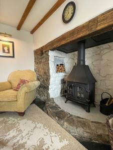 een woonkamer met een stenen open haard met een bank en een klok bij The Old Post House - Historic Dartmoor Home in Tavistock