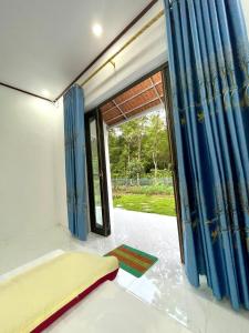 a room with blue curtains and a sliding glass door at The Garden Homestay Ninh Bình in Ninh Binh