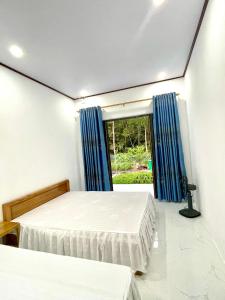 two beds in a room with blue curtains and a window at The Garden Homestay Ninh Bình in Ninh Binh