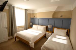 1 dormitorio con 2 camas y ventana en Salamander Guest House en Stratford-upon-Avon