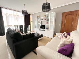 een woonkamer met 2 stoelen en een zwart-witte bank bij Apartamentos Gran Via in Salamanca
