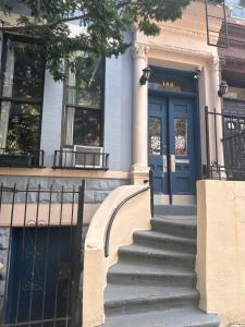 um edifício com uma porta azul e escadas em frente em Macaw Guest House em Nova York