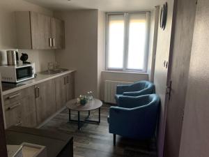 eine kleine Küche mit zwei blauen Stühlen und einem Tisch in der Unterkunft Appartement Romantique in Masevaux
