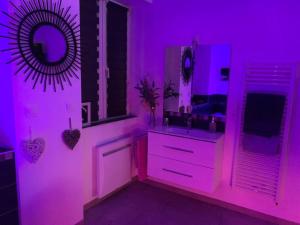 ein lila Badezimmer mit einem Waschbecken und einem Spiegel in der Unterkunft Appartement Romantique in Masevaux