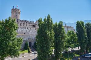 um edifício com uma torre e árvores em frente em B&B La Loggia Del Castello em Trento
