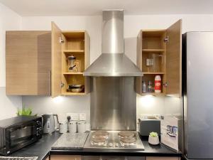 a kitchen with a stove with a large pot at Cityfront Cosy Apt Near City Centre & Etihad Stadium, Free Parking in Manchester