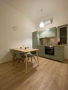 una cocina con armarios verdes, mesa y sillas en Ci Vediamo Al Mare, en Metaponto
