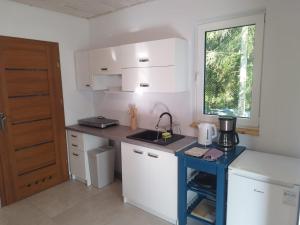 a small kitchen with white cabinets and a window at Budlejowy domek in Kołczewo