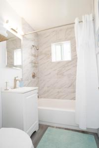 La salle de bains blanche est pourvue d'une baignoire et d'un lavabo. dans l'établissement Seaside Point Loma Home W Outdoor Patio, à San Diego