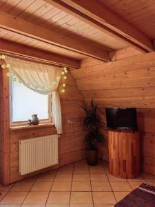 um quarto com uma janela e uma televisão num quarto de madeira em Agroturystyka "U Macieja" em Teleśnica Oszwarowa