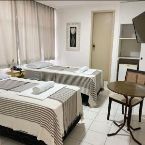 um quarto de hotel com duas camas e uma mesa em Majestic Hotel em Campina Grande