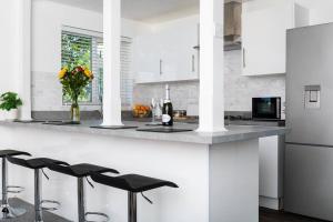 a white kitchen with a counter with black stools at Newly Renovated 2 Bed house in Penryn