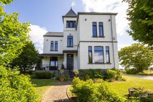 une ancienne maison blanche avec une tourelle dans l'établissement LE MANOIR DE LA VALETTE, à Florennes