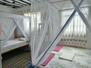 a bedroom with two beds with mosquito nets at Kacho House in Jambiani