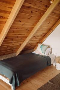 a bed in the attic of a room with wooden ceilings at Osada Przejrzysko in Jordanów