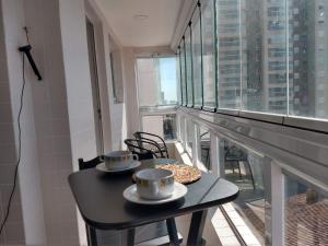 a table with two cups and donuts on a balcony at Aconchegante Apto Praia do Centro in Itanhaém