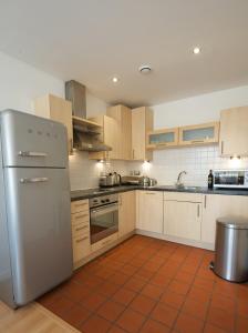 uma cozinha com um frigorífico de aço inoxidável e armários em Stay Deansgate Apartments for 14 nights plus em Manchester