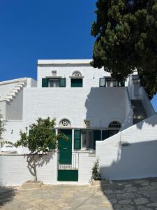 una casa bianca con porte verdi e un albero di Aeris Tinos Suites a Panormos
