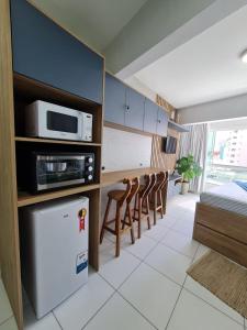 Una habitación con cocina con microondas y sillas. en Studio Beira Mar - Em frente RODA GIGANTE, en Balneário Camboriú