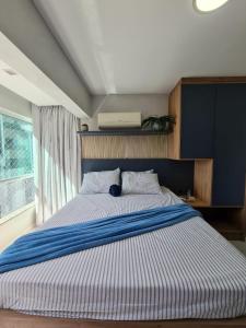 1 dormitorio con 1 cama con rayas azules y blancas en Studio Beira Mar - Em frente RODA GIGANTE, en Balneário Camboriú 18 fotos más