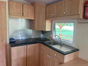 a kitchen with wooden cabinets and a sink and a window at Le Cottage in Fraize