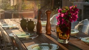 una mesa de madera con platos y un jarrón de flores en Magia22 - Place for the soul!, en Káthikas