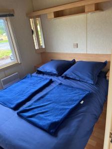 a large blue bed with blue sheets and pillows at Le Cottage in Fraize