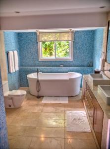 a bathroom with a tub and a toilet and a window at Sunny Vacation Villa No 48 in San Rafael del Yuma