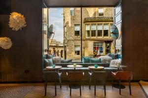 un restaurante con 2 mesas y sillas y una ventana en Motel One Edinburgh-Royal en Edimburgo