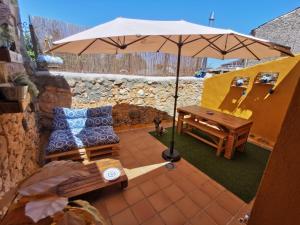 un patio con sombrilla, sofá y mesa en Casita Pirón, en Adrada de Pirón
