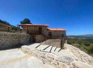 una casa de piedra en una colina con una pared de piedra en Casa Rosmaninho - Izei, en Chaves