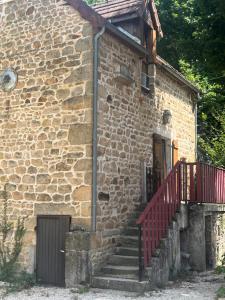 um edifício de tijolos com uma escada vermelha ao lado de uma porta em maison Saint Berain sur Dheune em Saint-Berain-sur-Dheune