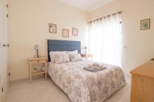 um quarto com uma cama com uma cabeceira azul e uma janela em Sunset Vau em Portimão