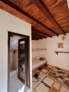 a room with a bed and a wooden ceiling at Onda Hostel Mompiche in Mompiche