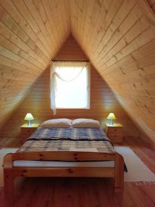 a bed in a wooden cabin with a window at Agroturystyka "U Macieja" in Teleśnica Oszwarowa