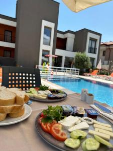 two plates of food on a table next to a pool at Eva Apart Kemer in Kemer