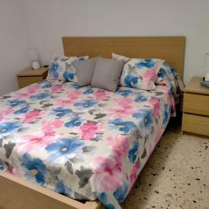 a bed with a floral comforter and two pillows at Le Casette di Nonna Rosa in Fontanarossa Catania Airport in Catania