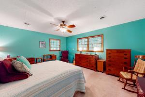a bedroom with blue walls and a bed with a ceiling fan at Pine Knoll Nest in Pine Knoll Shores