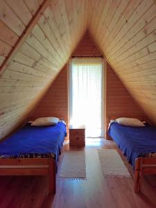 1 dormitorio en el ático con 2 camas y ventana en Agroturystyka "U Macieja", en Teleśnica Oszwarowa