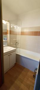 ein Badezimmer mit einer Badewanne, einem Waschbecken und einem Spiegel in der Unterkunft Appartement coeur de station village Saint Francois Longchamp in Saint-François-Longchamp