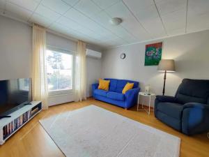 a living room with two blue couches and a tv at Polku Apartaments in Imatra