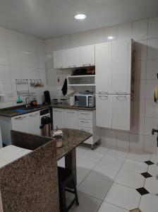 cocina con armarios blancos y encimera en Casa em Itaipu, en Niterói