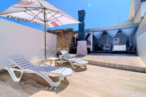 two lounge chairs and an umbrella on a patio at Cueva con jacuzzi a 20 minutos de Valencia in Benaguacil