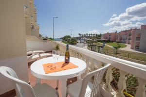 - une table blanche avec une bouteille de vin sur le balcon dans l'établissement Sunset Vau, à Portimão
